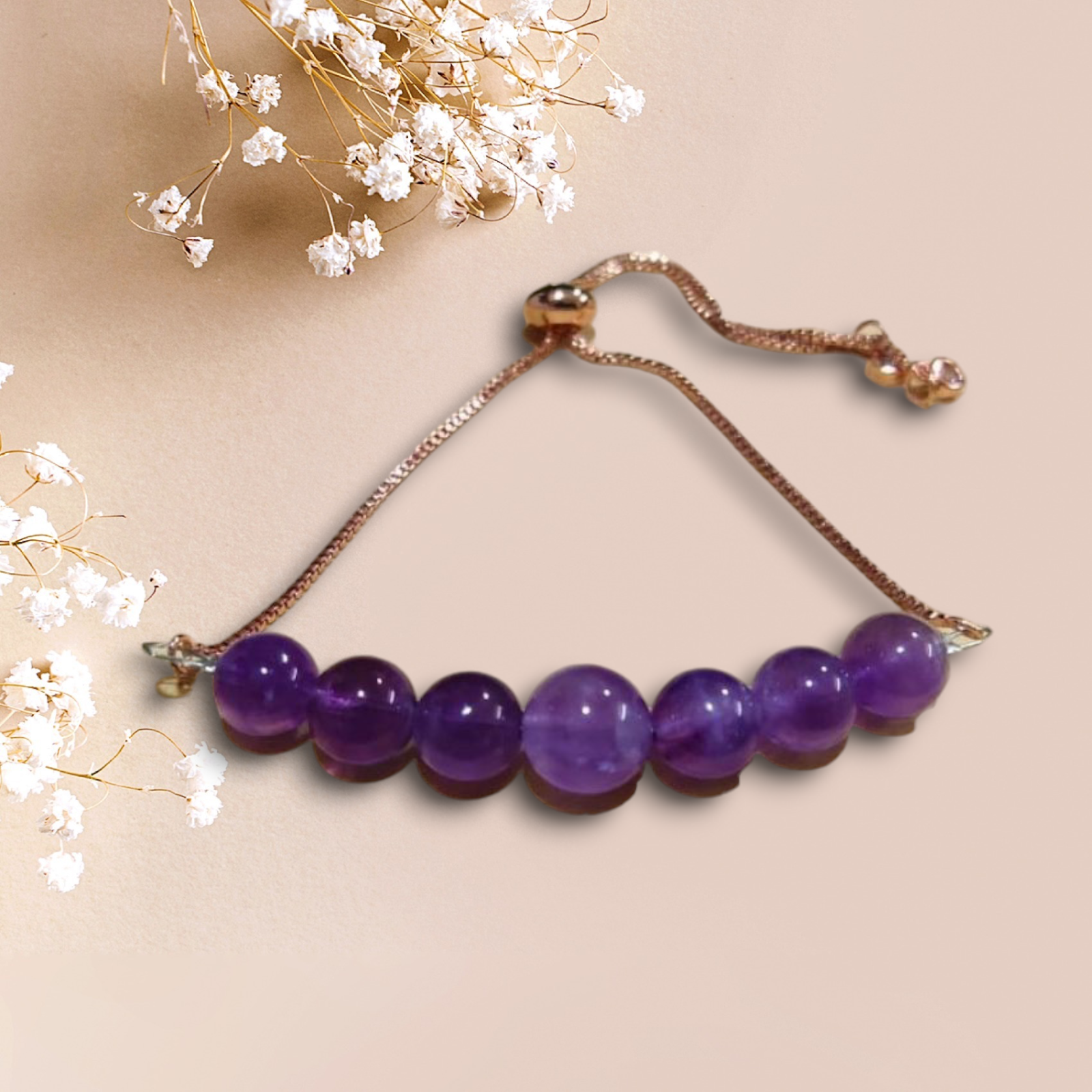 Purple beaded bracelet on a beige background with white flowers