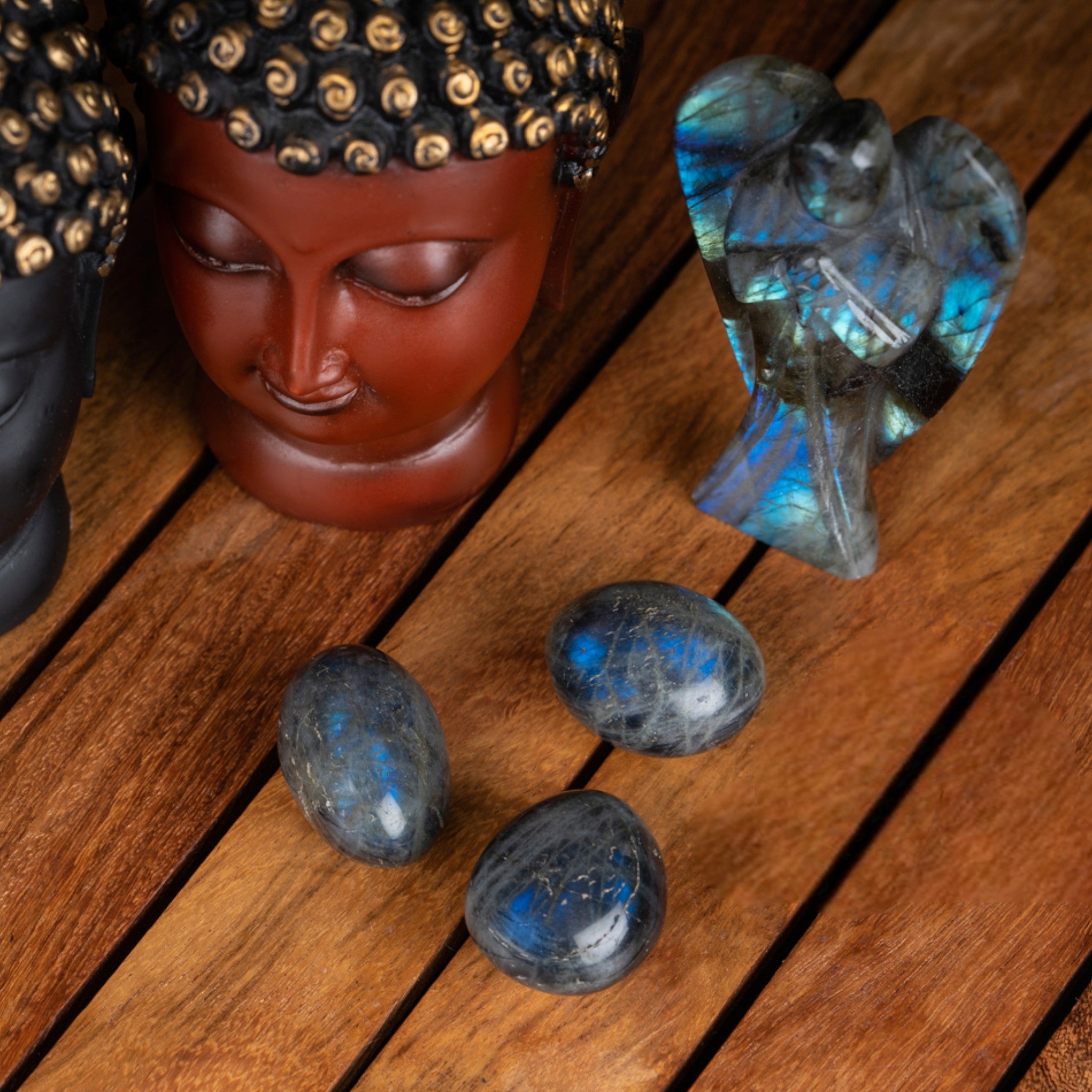 This image features a collection of labradorite stones, known for their captivating play of color and metallic sheen. The stones are displayed on a wooden surface, surrounded by items that enhance their mystical and spiritual associations.