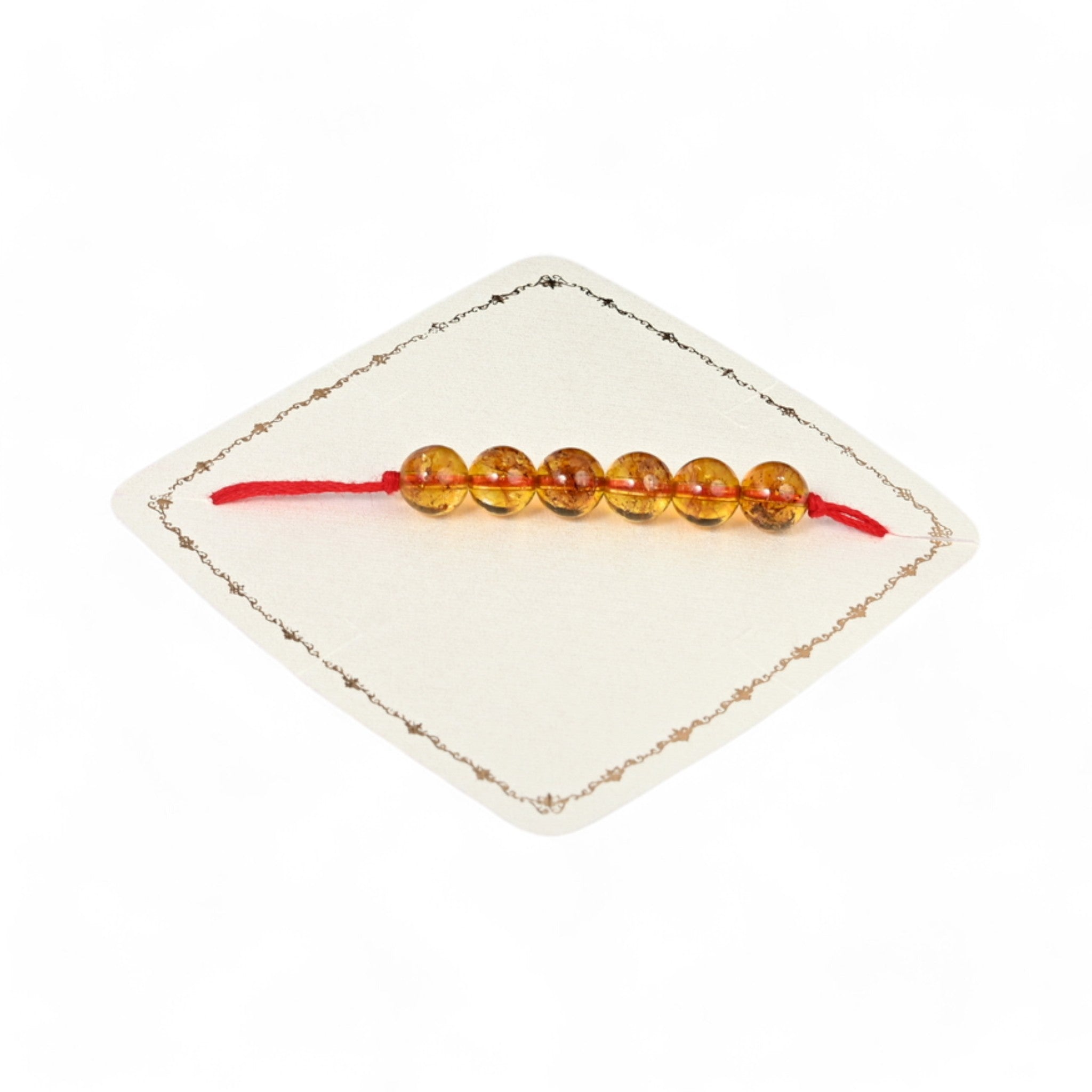 A single-strand citrine rakhi displayed on a white cushion with a red thread.