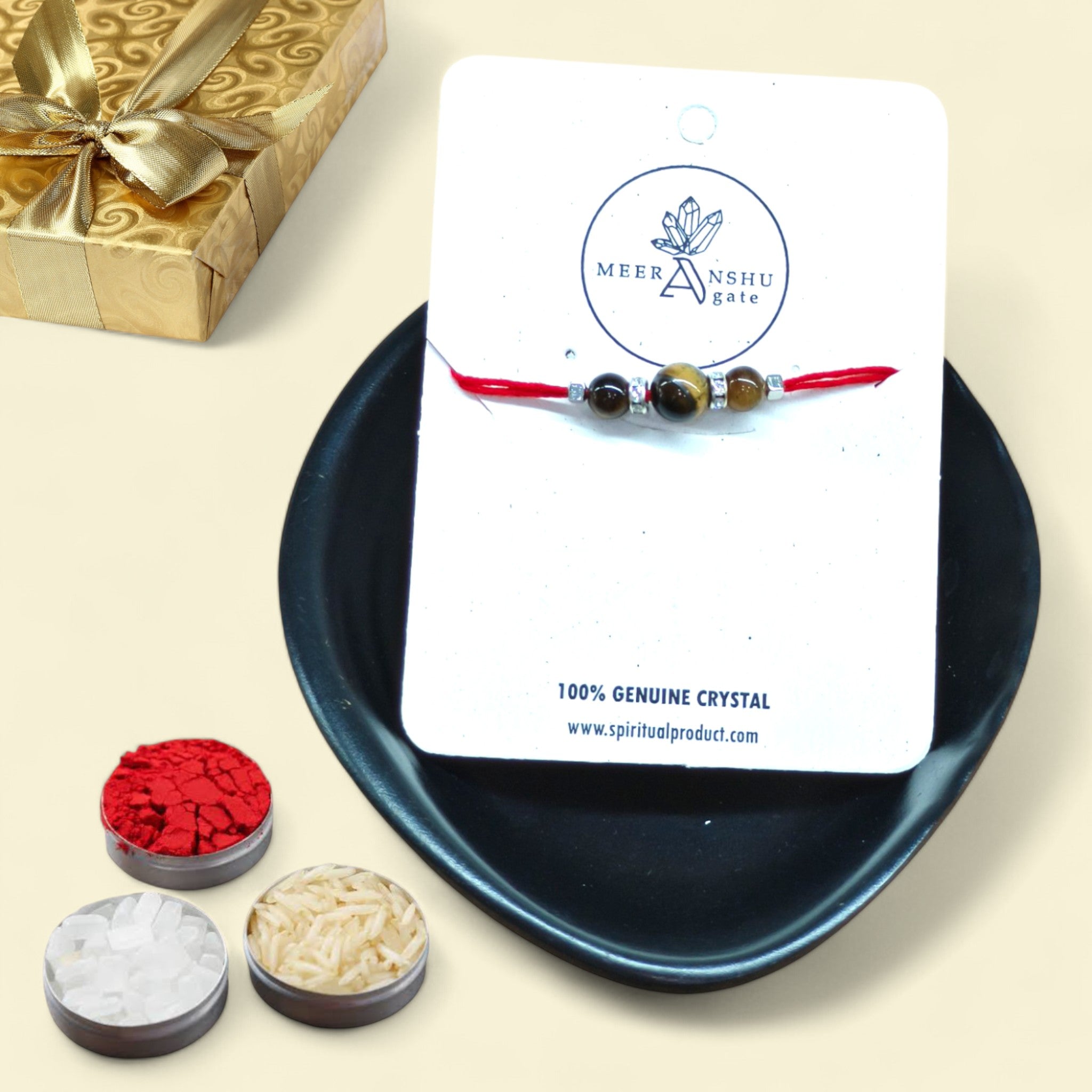 A handcrafted Rakhi bracelet made with three genuine, original Tiger Eye gemstone beads and silver color spacers on a red thread, presented in a traditional Raksha Bandhan gift setting with puja supplies.